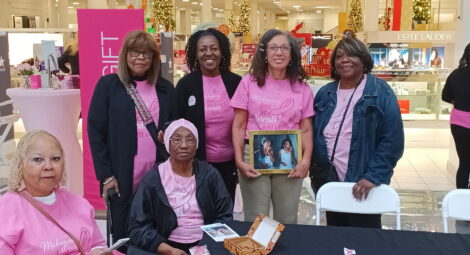Women sitting at event table pose for photo