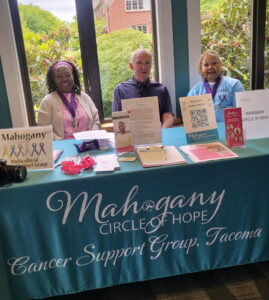 two women and a man pose for photo at event table