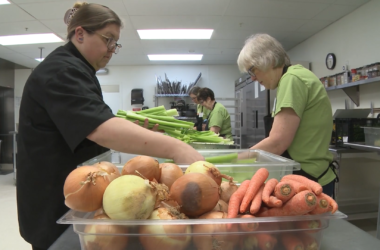 Group of 4 volunteers working in the kitchen prepping vegetables.