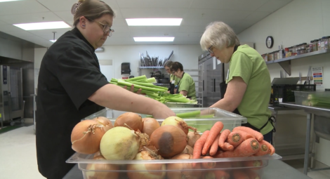 Group of 4 volunteers working in the kitchen prepping vegetables.