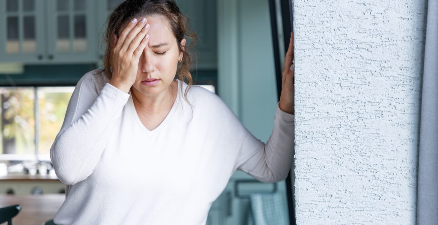 young woman appears in pain with hand on forehead