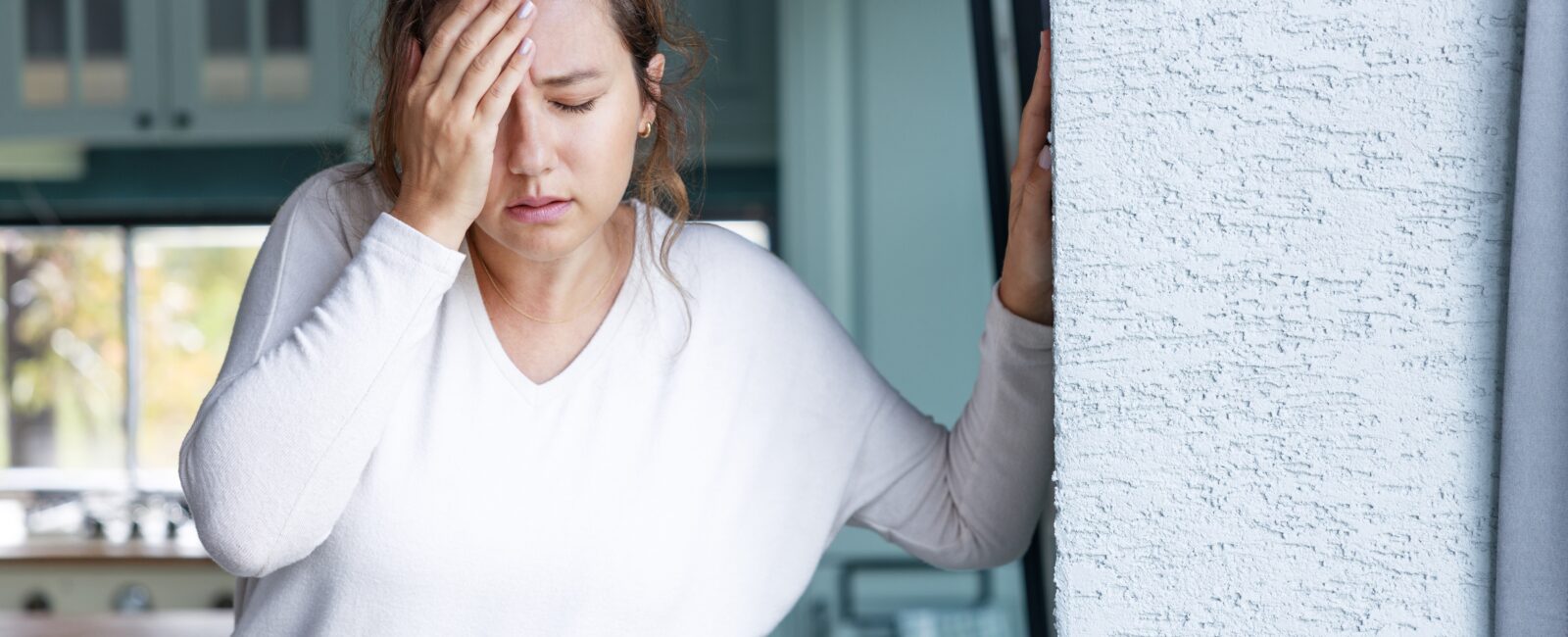 young woman appears in pain with hand on forehead