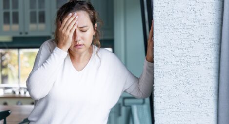 young woman appears in pain with hand on forehead