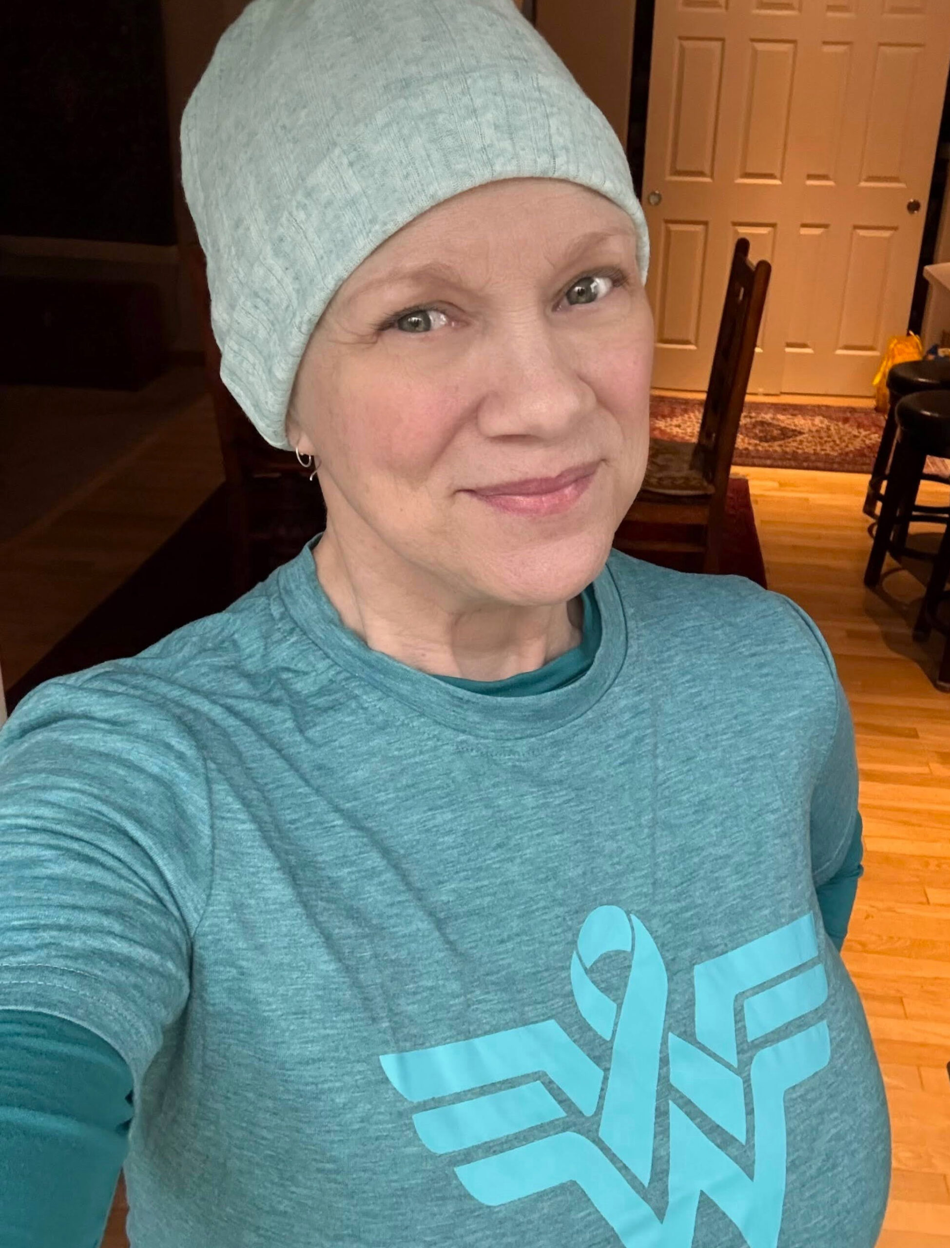 smiling woman wearing teal shirt and beanie