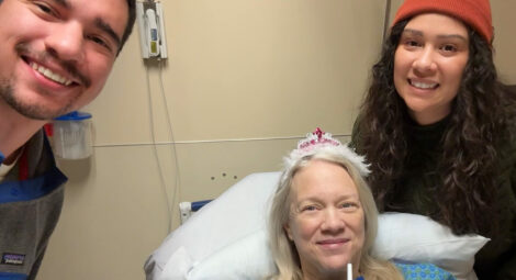 woman in hospital bed wearing tiara with son and daughter