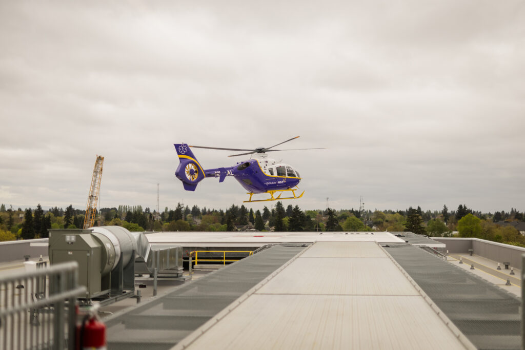 Helicopter, Purple and yellow helicopter hovering above a rooftop helipad