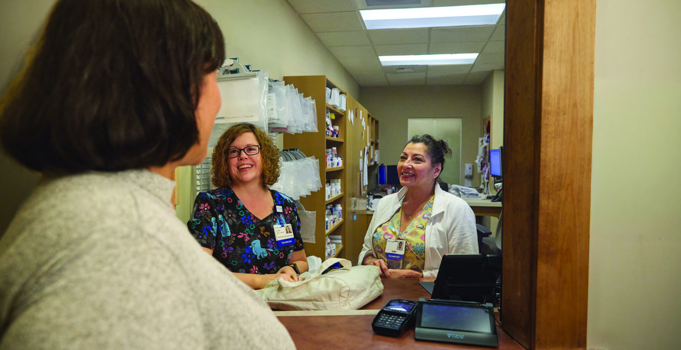 Three women talking at pharmacy window