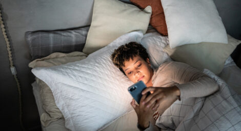 Woman lying in bed looking at her phone
