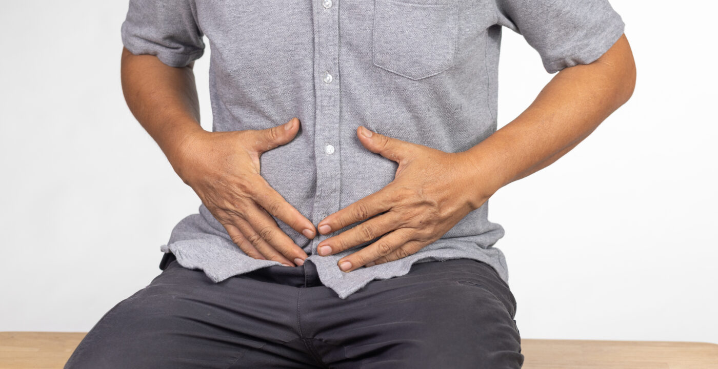 man sitting and holding lower abdomen