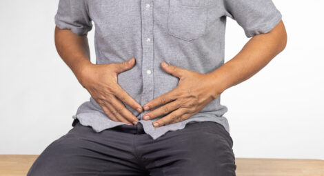 man sitting and holding lower abdomen