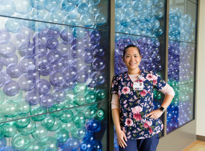 Mary Bridge RN Precious stands in front of the glass float wall.