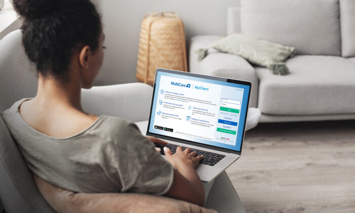 Woman using laptop computer on sofa, logging into her MyChart account.
