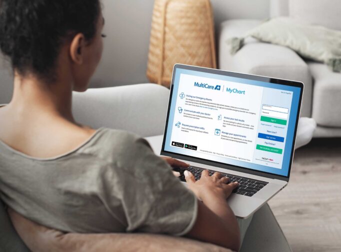 Woman using laptop computer on sofa, logging into her MyChart account.