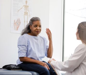 Woman on a medical table talking to her doctor.