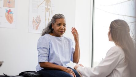 Woman on a medical table talking to her doctor.