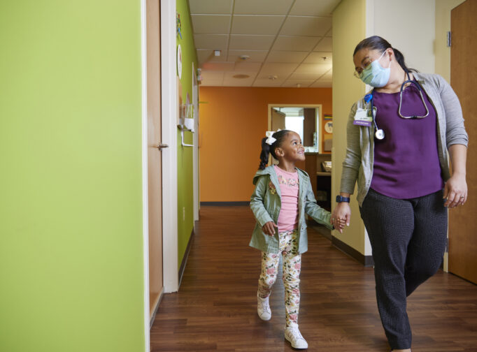 Little girl walks through doctor's office with her doctor