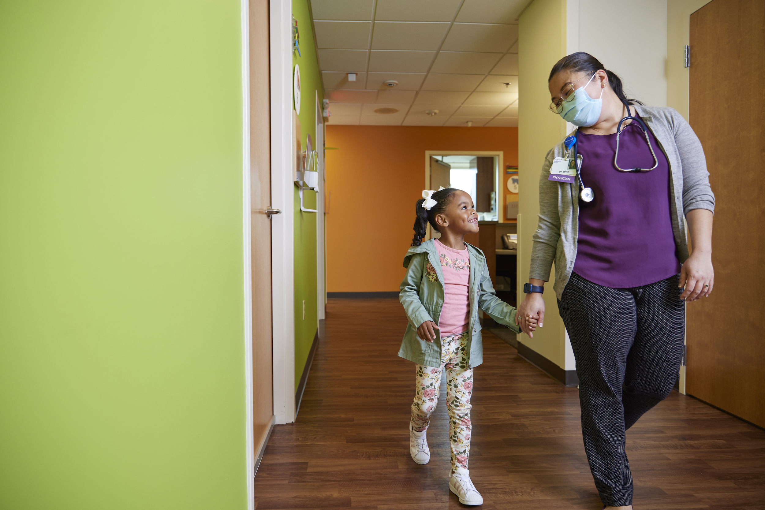 Little girl walks through doctor's office with her doctor