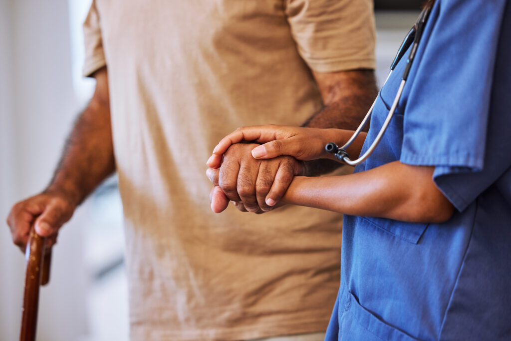 Caregiver providing support for a patient walking with a cane.