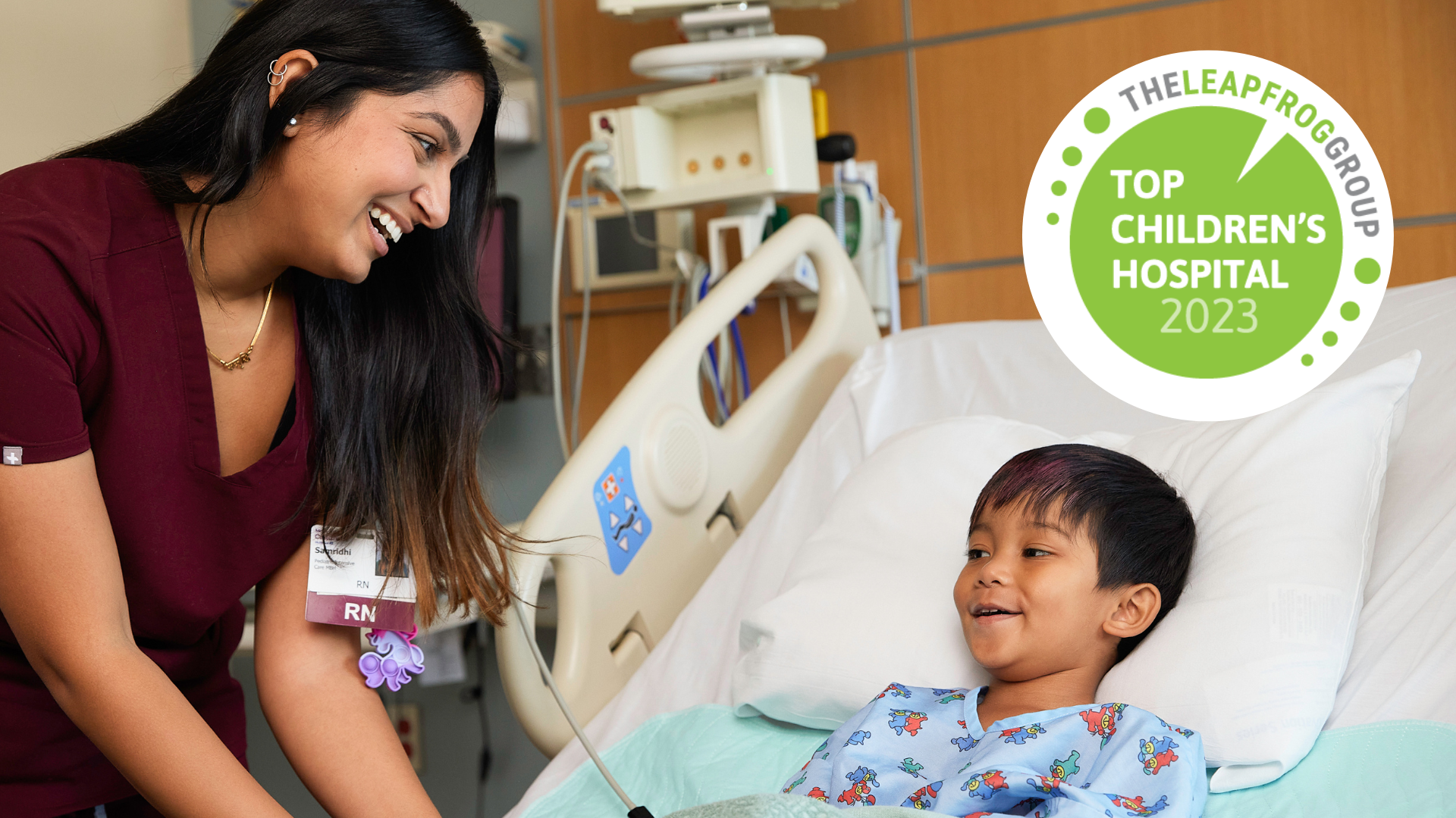 Nurse smiles at young boy in hospital bed