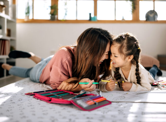 Mother and daughter bonding while drawing in their cozy bedroom