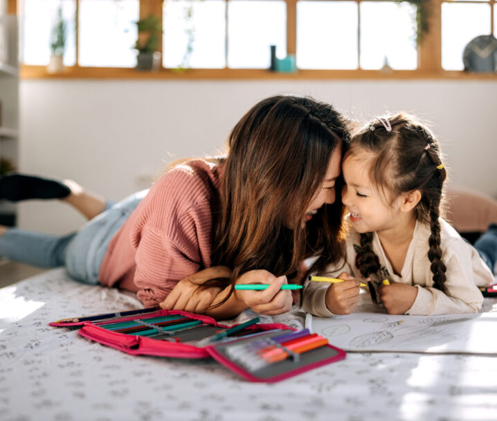 Mother and daughter bonding while drawing in their cozy bedroom