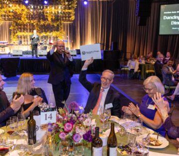 At a banquet table, Bill Robertson holds up a large envelope that reads Howard S. Wright.