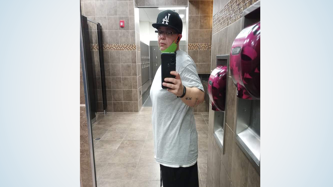 Woman in T-shirt and ball cap poses for a mirror selfie