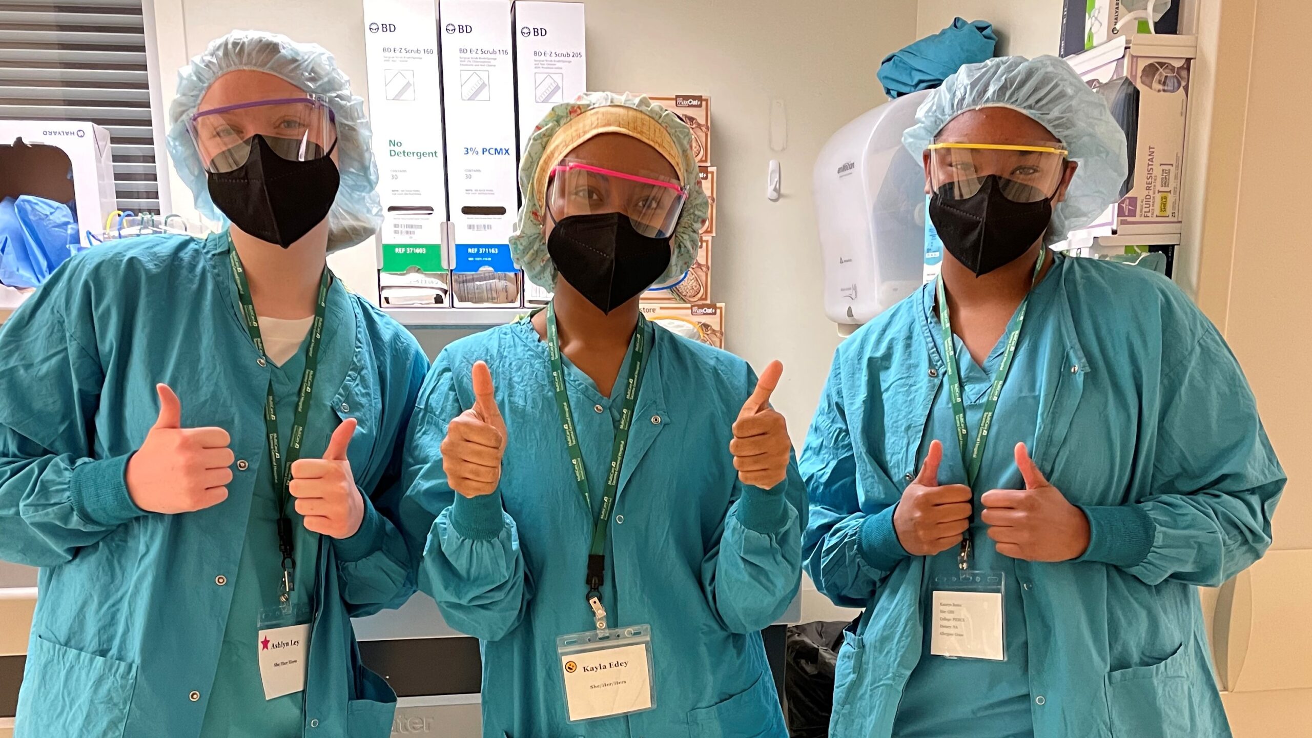 Three M.A.S.H. camp participants dressed in surgical scrubs, masks and protective eye gear.