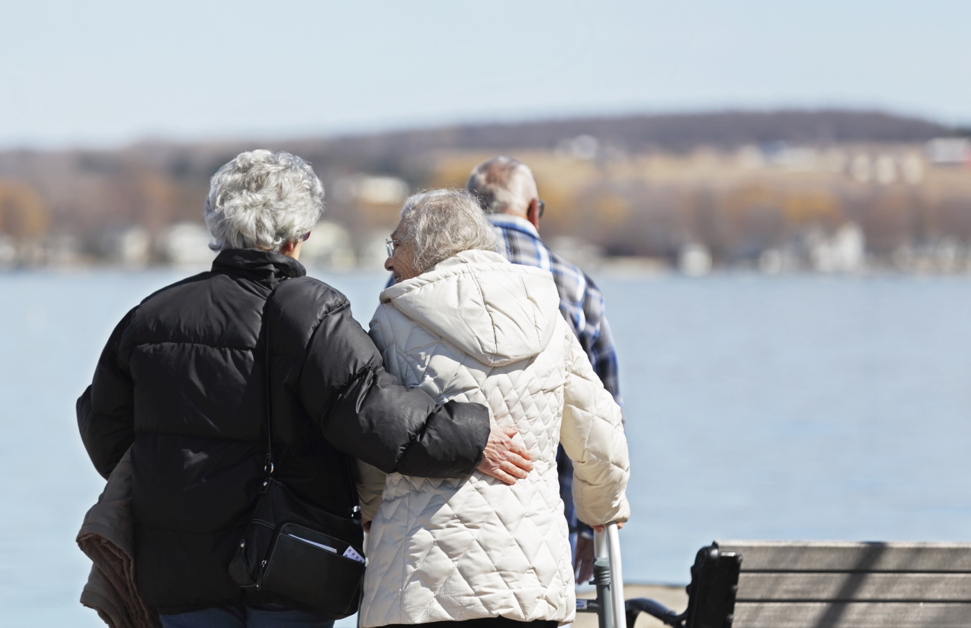 Two older women and one older man walking alongside a body of water
