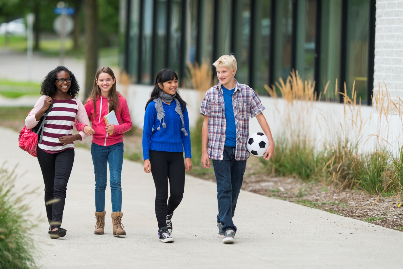 A group of preteens walk down a sidewalk