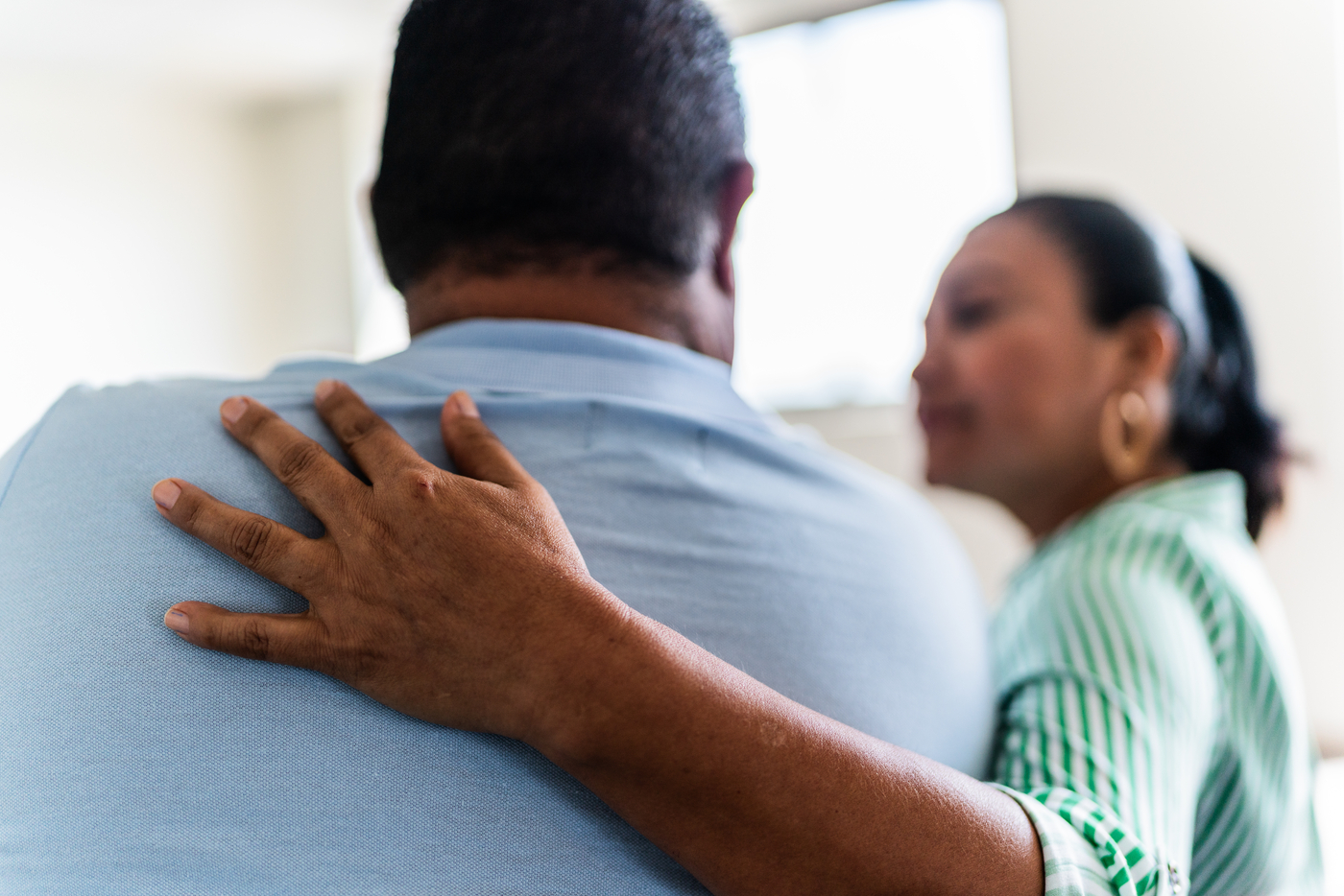 Woman puts a comforting arm around man’s shoulders
