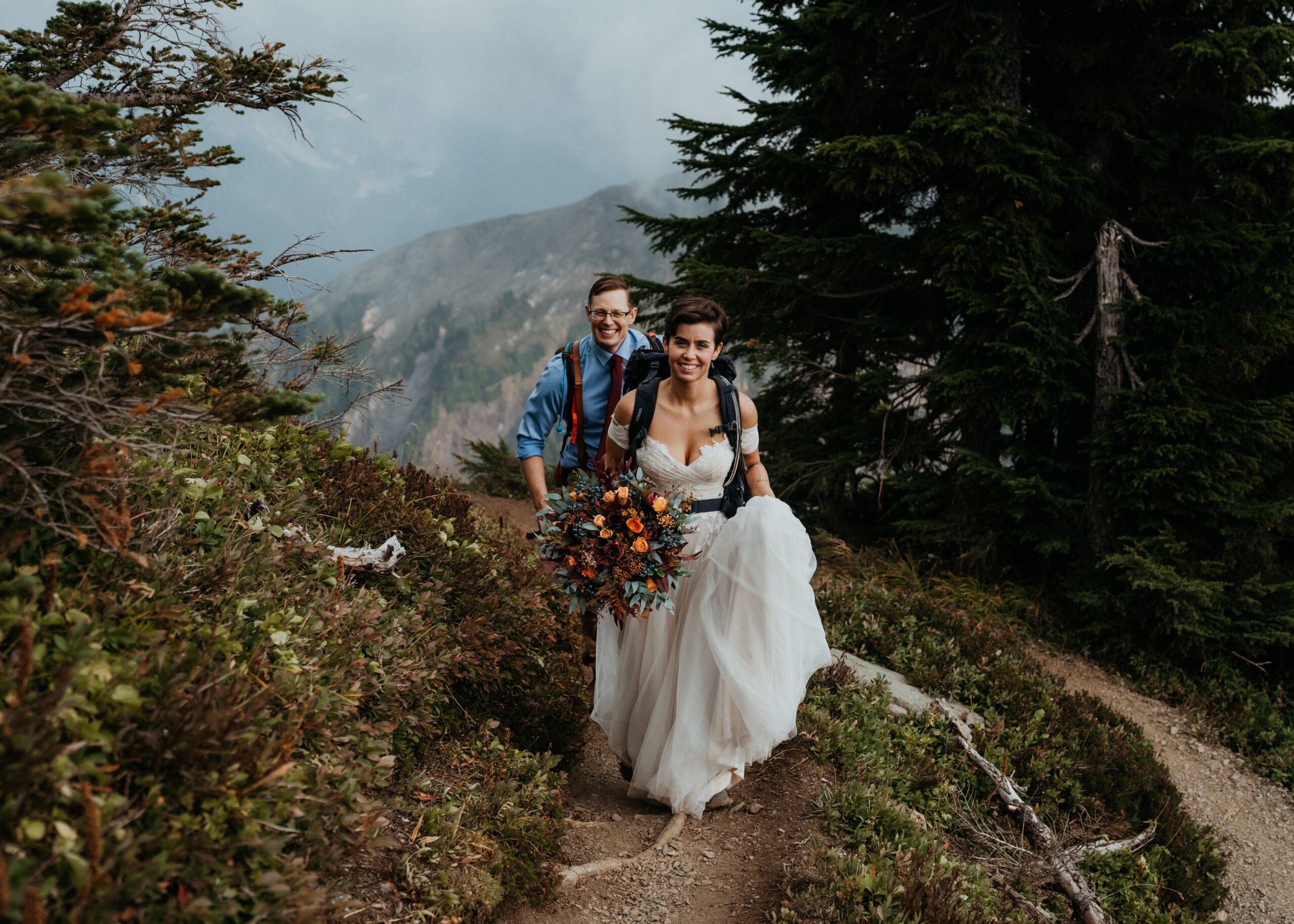 Bride and groom hiking on a mountain trail