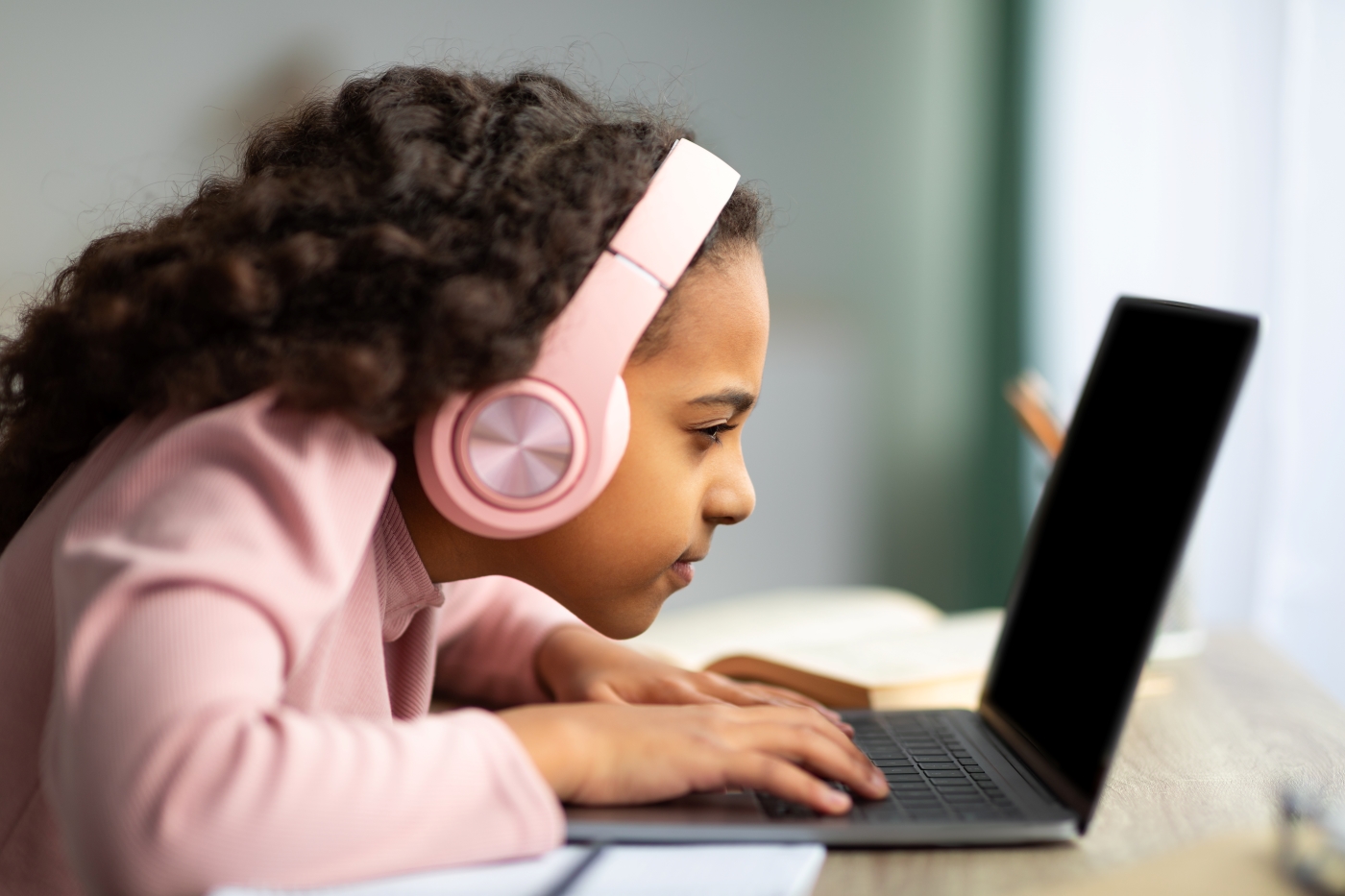 Young girl wearing headphones and squinting at a laptop
