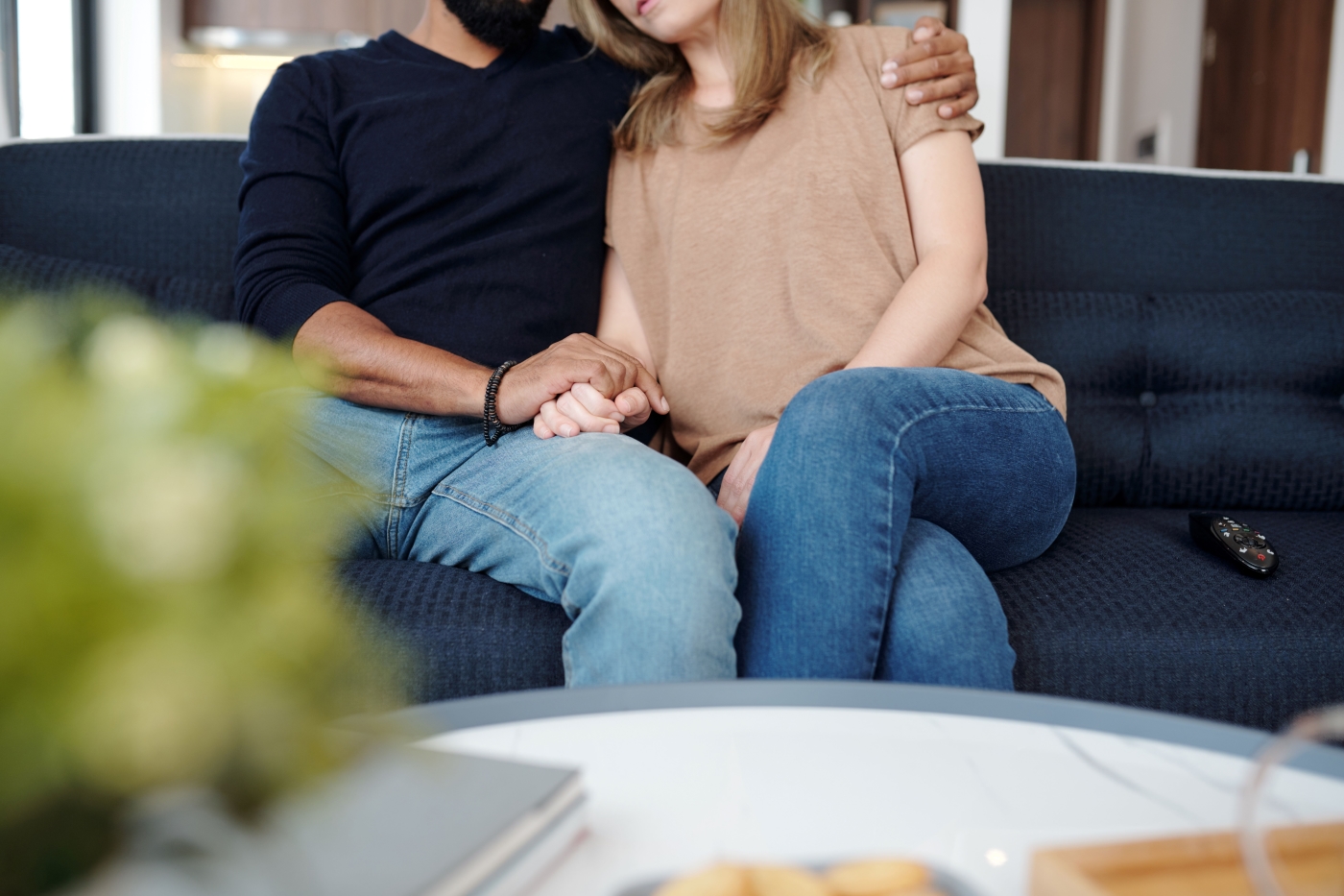 A man and a woman sitting on a blue couch holding hands