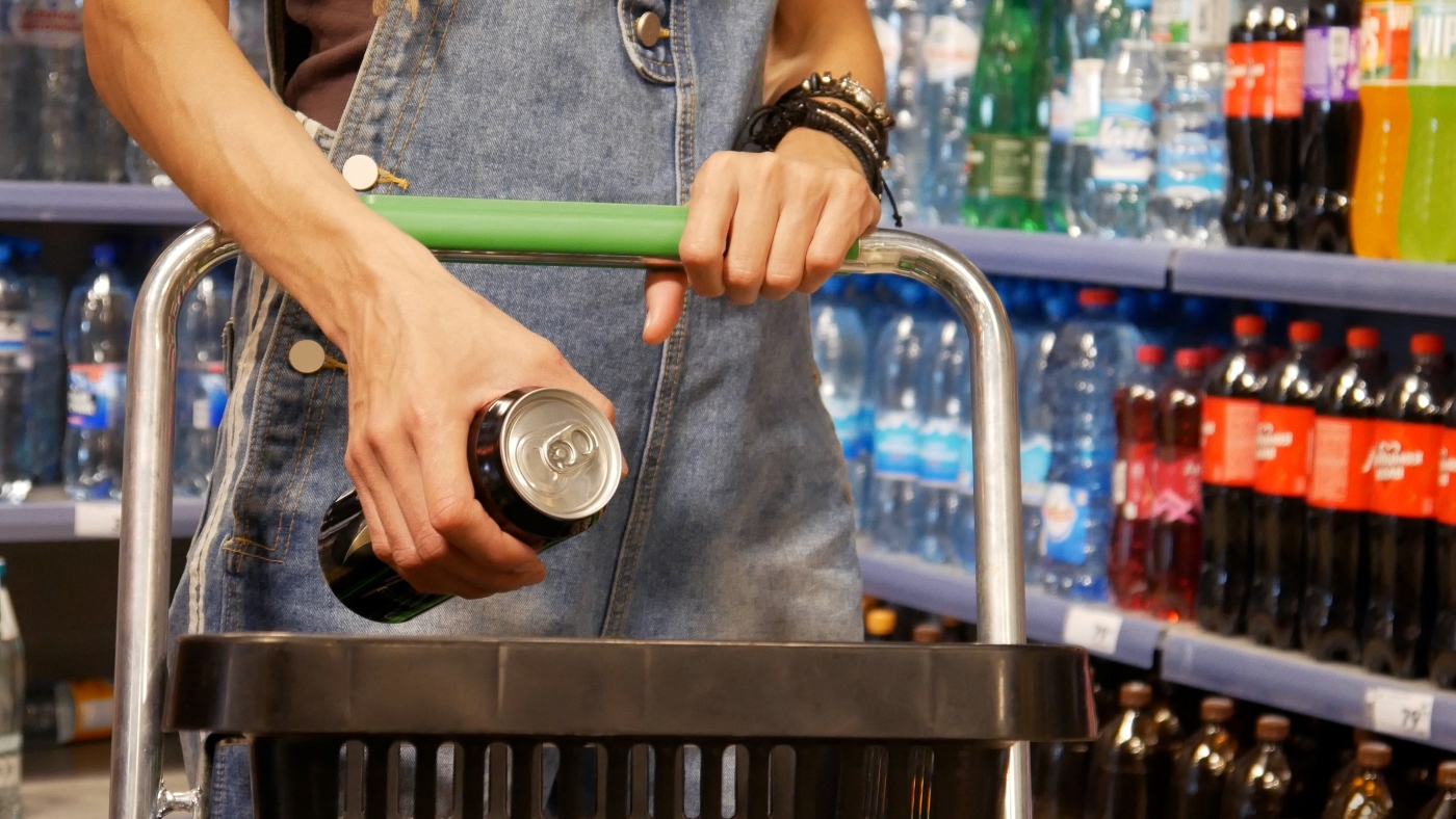 Person holding a canned energy drink while shopping