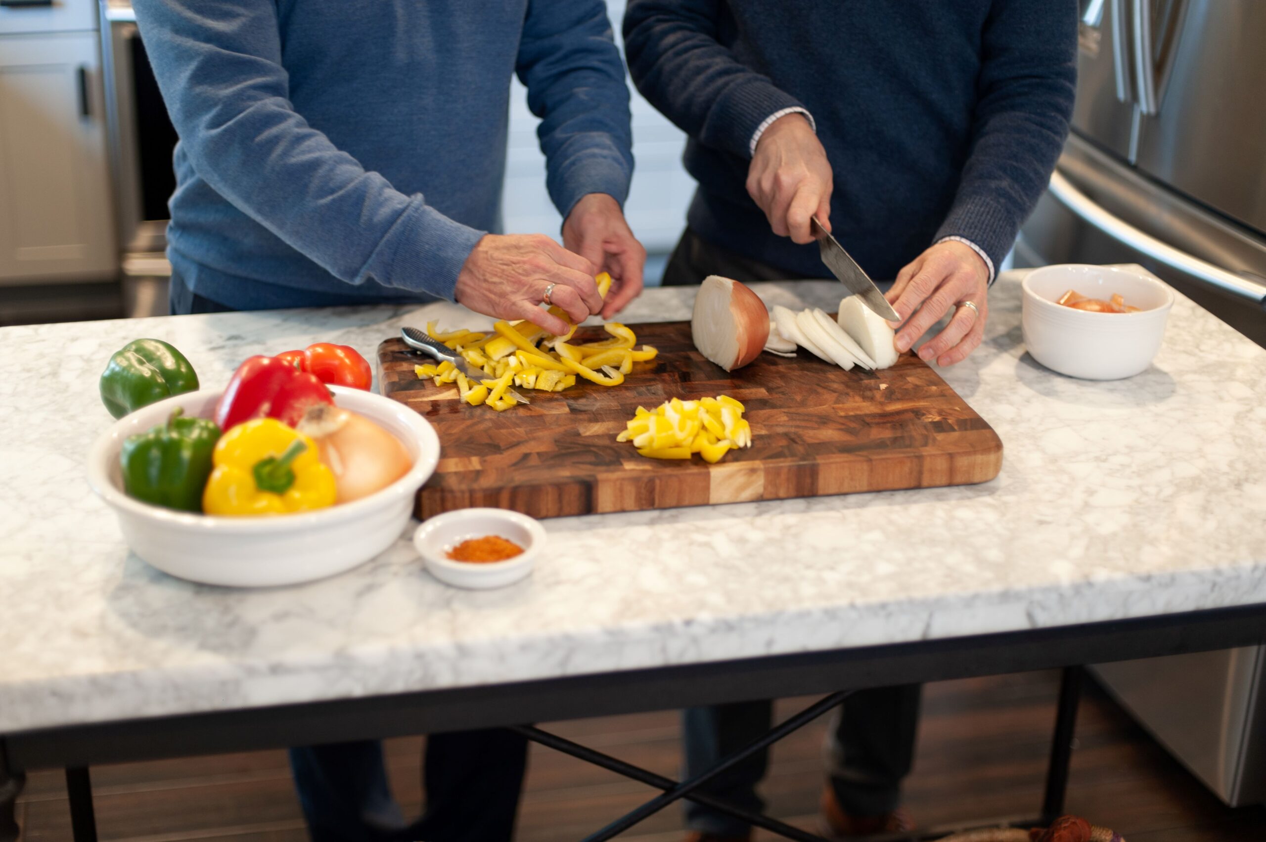 Two men in a kitchen chopping vegetables