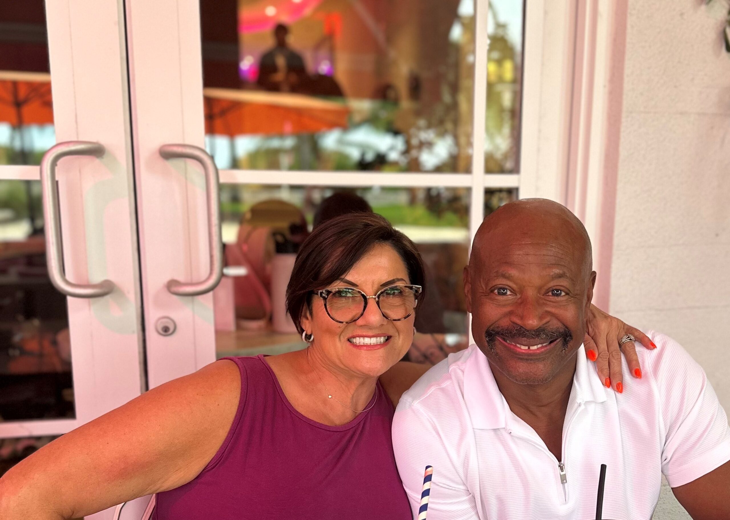 Woman and man smile for a photo in front of French doors