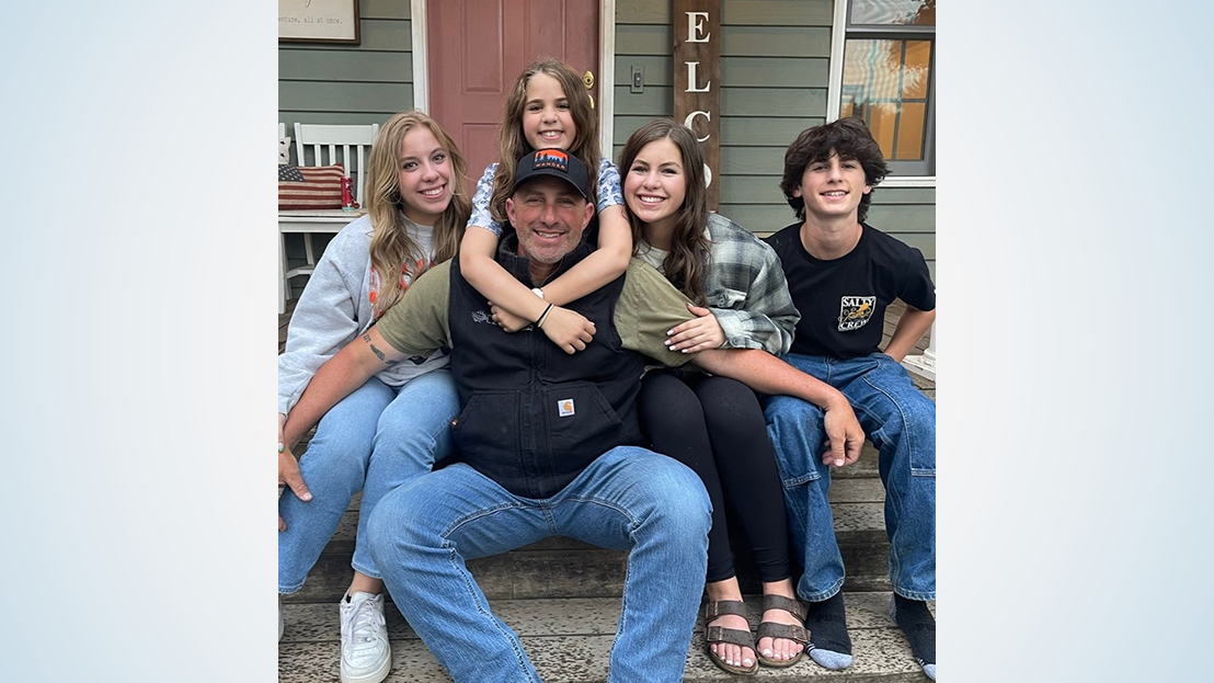 Man sitting on steps with his four children