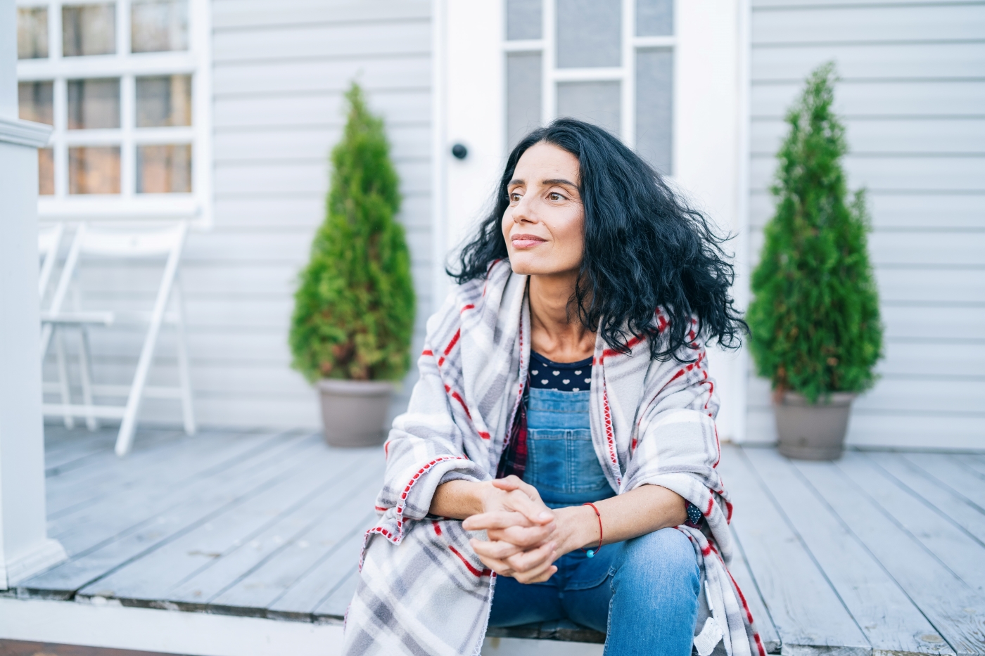 Woman sitting on porch wearing a plaid jacket