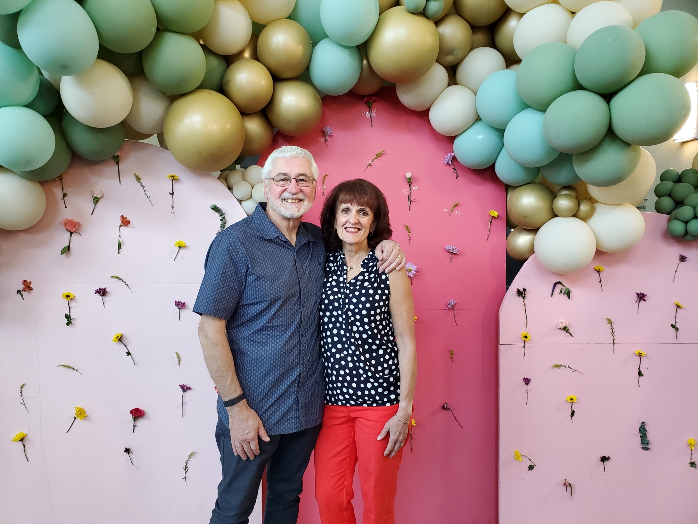 Man and woman stand underneath balloon arch