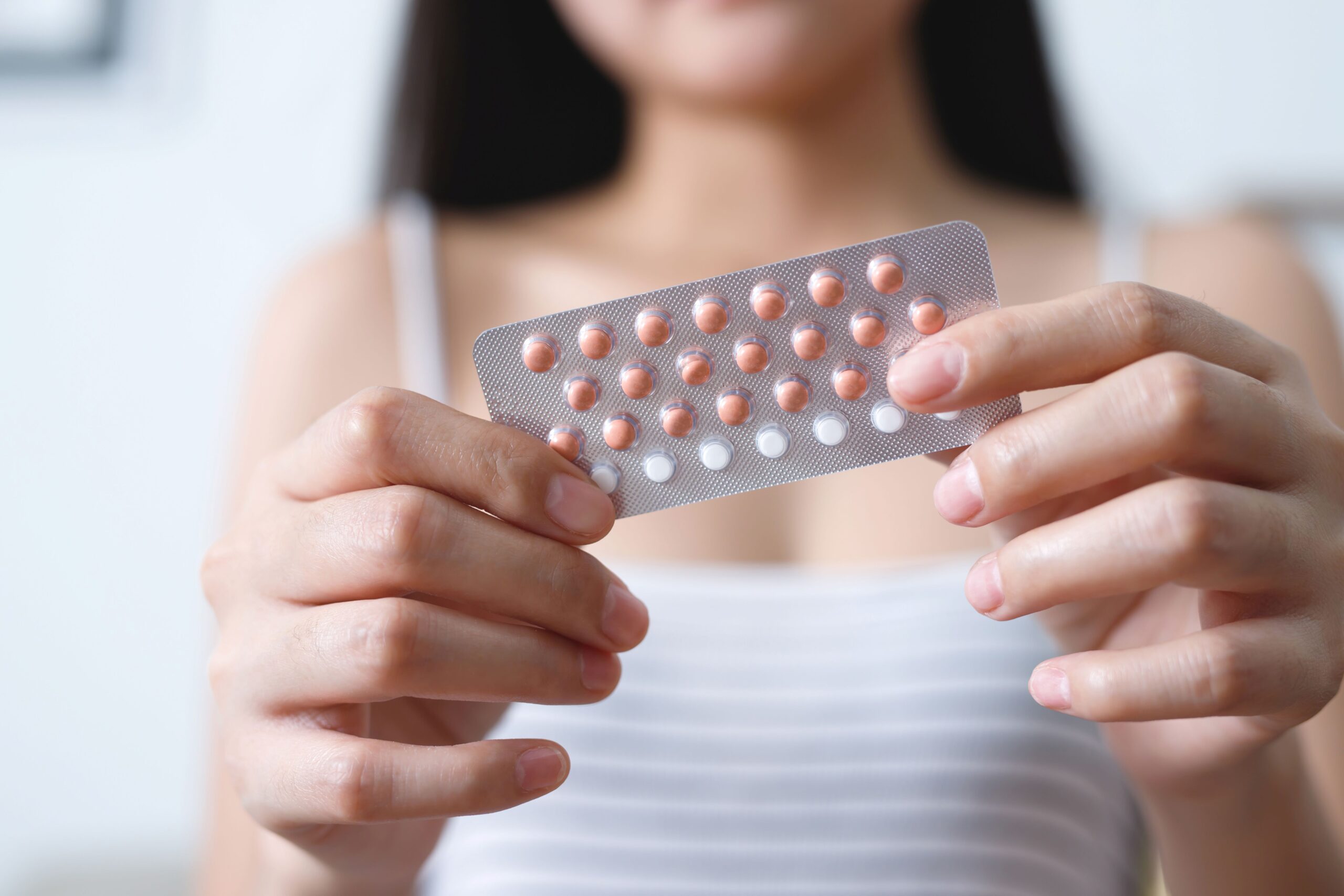 Young woman holding a pack of birth control pills