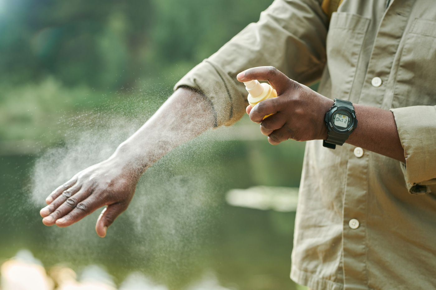 person spraying arm with bug spray