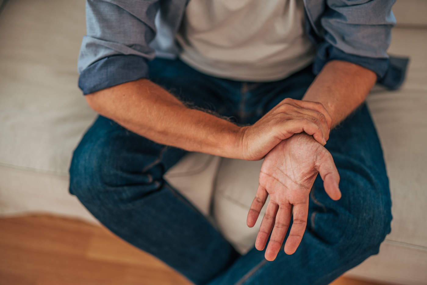 Man sitting on couch holding wrist with opposite hand