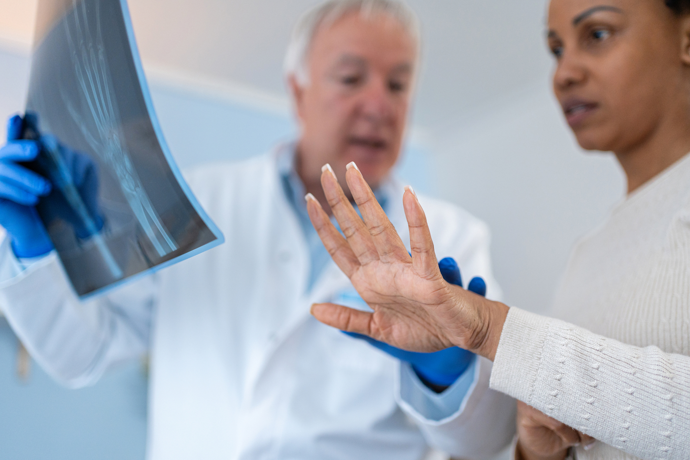 doctor holding X-ray of wrist as patient extends hand