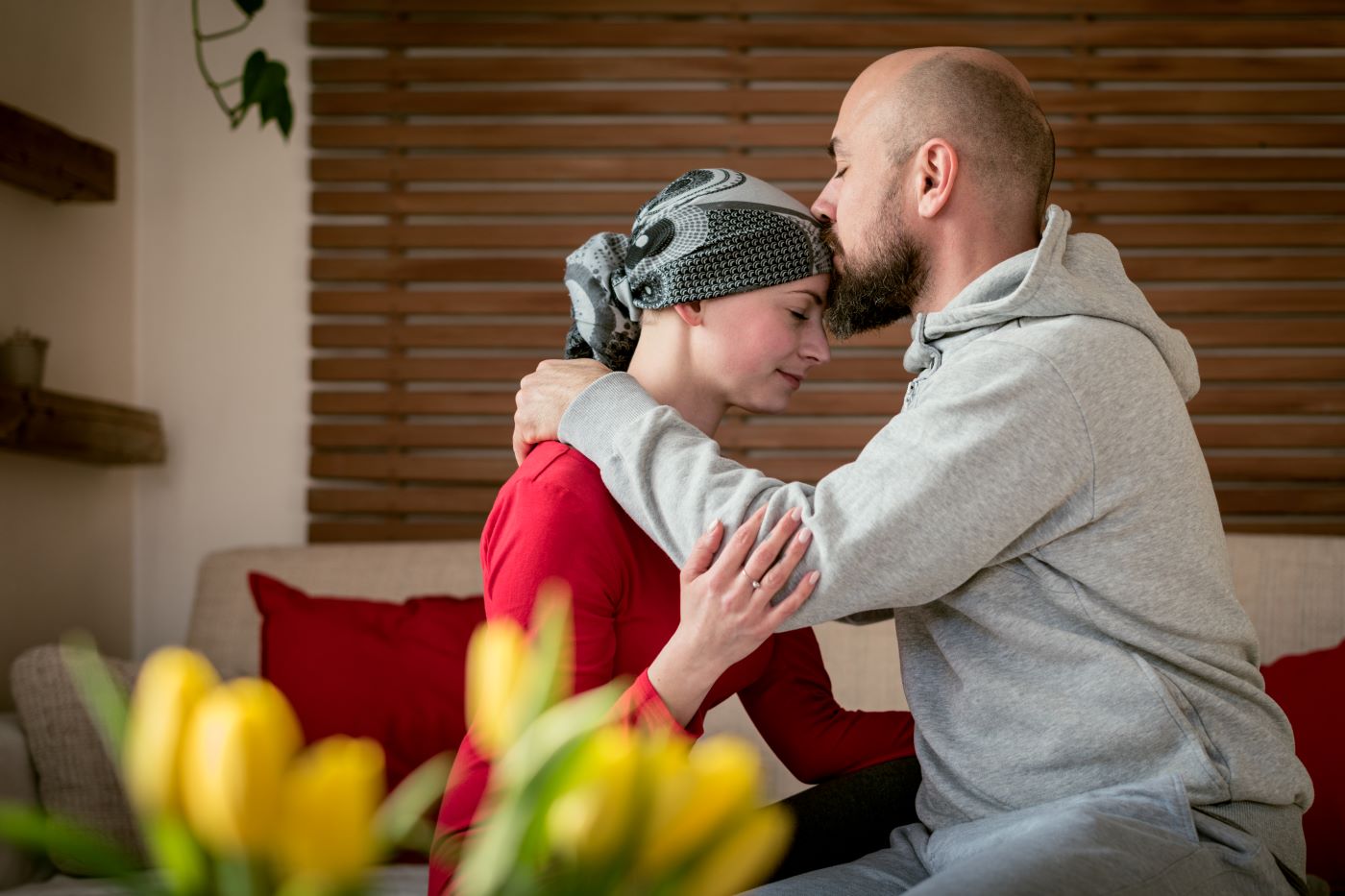 man kisses top of woman’s head