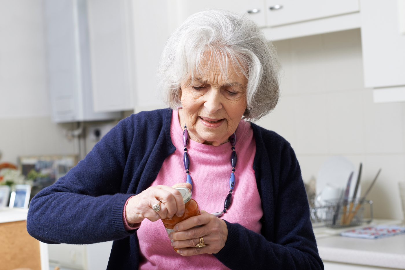 elderly woman struggling to open jar