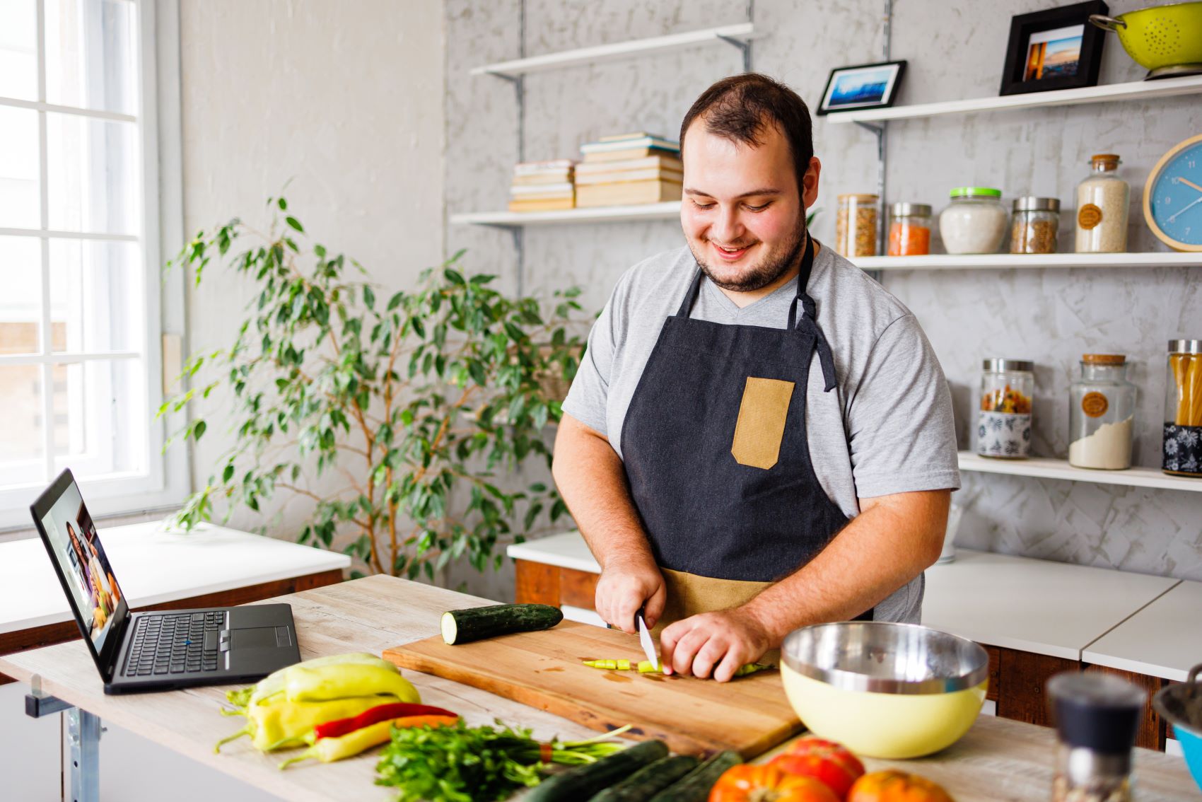 man wearing apron cutting a cucumber