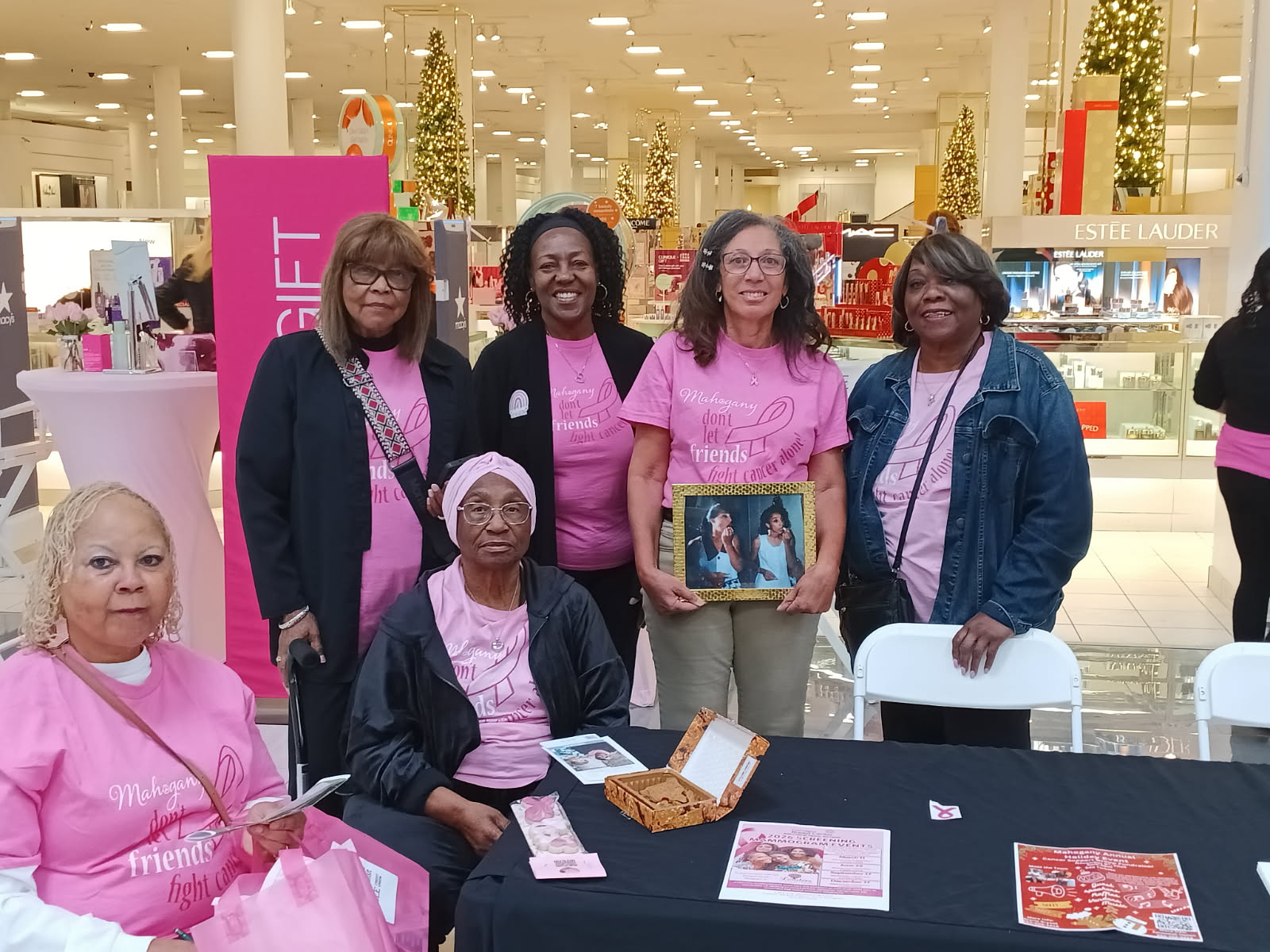 Women sitting at event table pose for photo