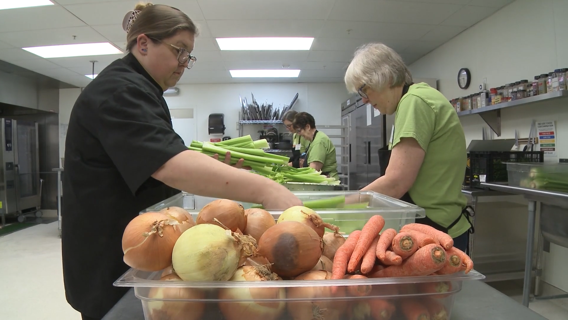 Group of 4 volunteers working in the kitchen prepping vegetables.