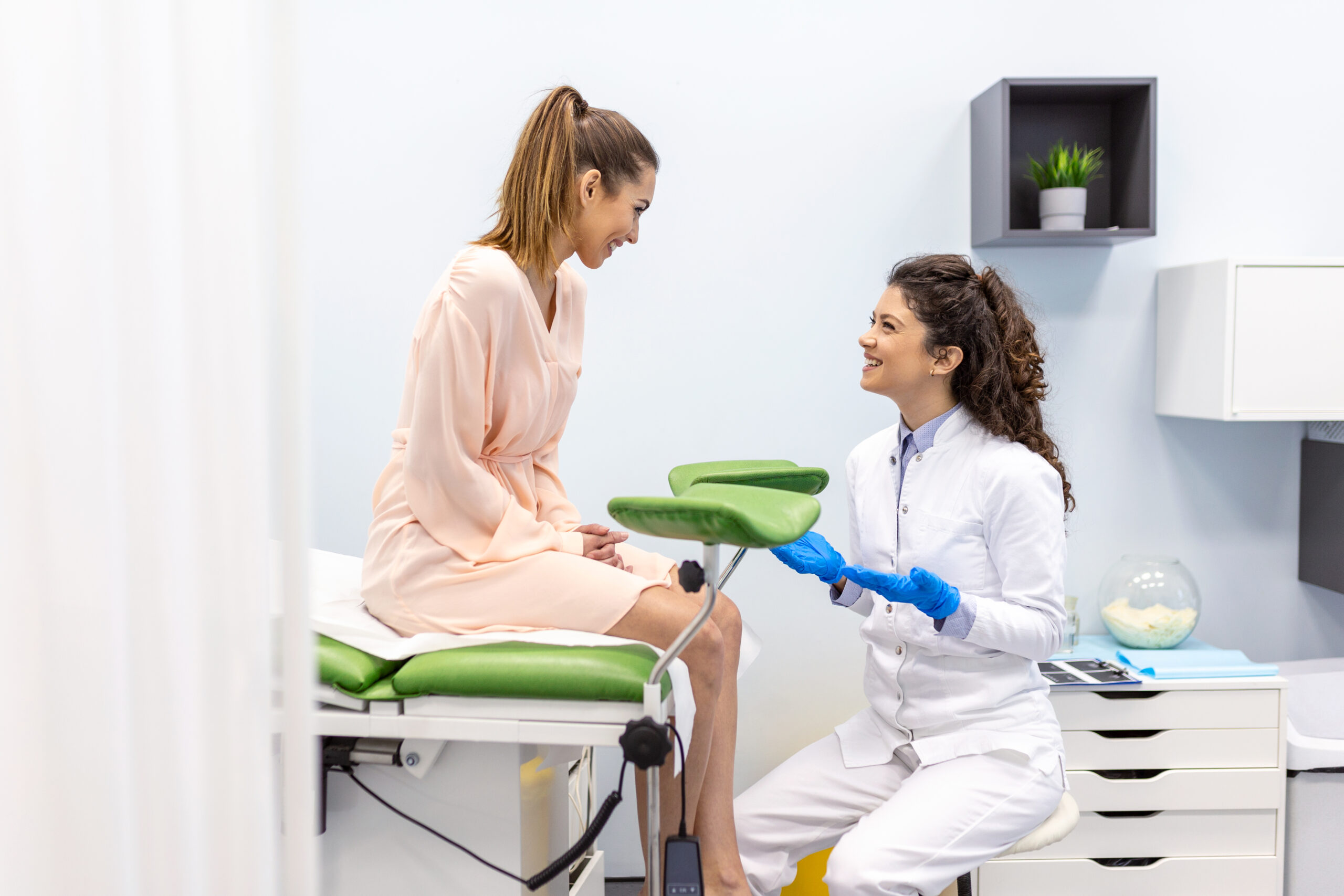 woman sits on clinic exam table talking with doctor